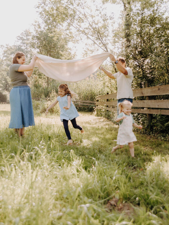 Natürliche Familienfotografie mit Eltern und Kindern im Garten bei einem gemeinsamen Familien-Fotoshooting